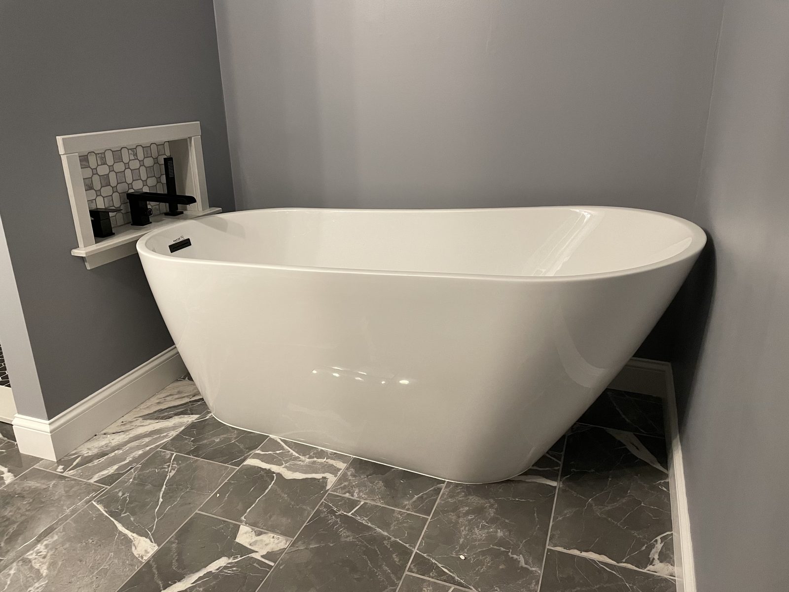 Finished bathroom remodel with a freestanding soaking tub and marble-look tile