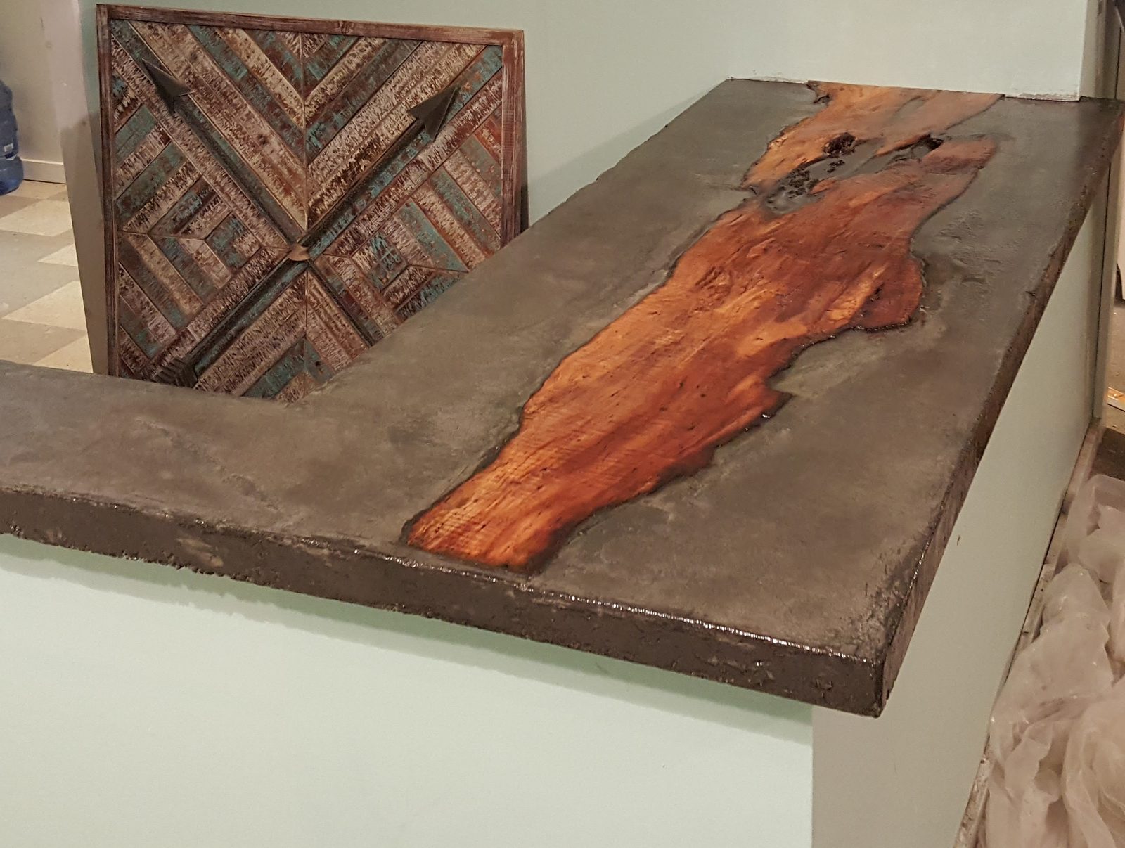 Custom concrete bar top with a live-edge wood inlay and reclaimed-wood panel